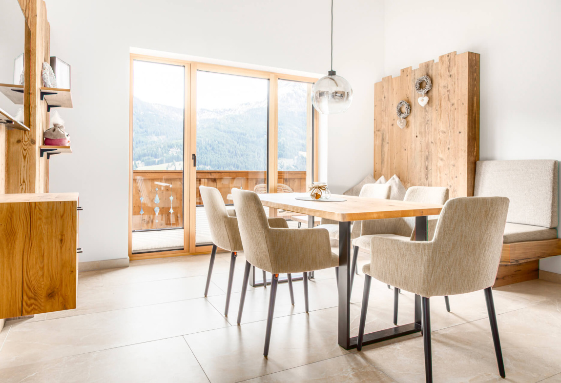 Moderne Ferienwohnung mit Esstisch, Stühlen und Bergblick aus großen Fenstern.